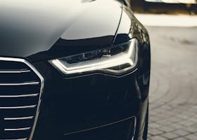 A sleek, modern luxury car showcasing its chrome detailing and LED headlights on a city street.